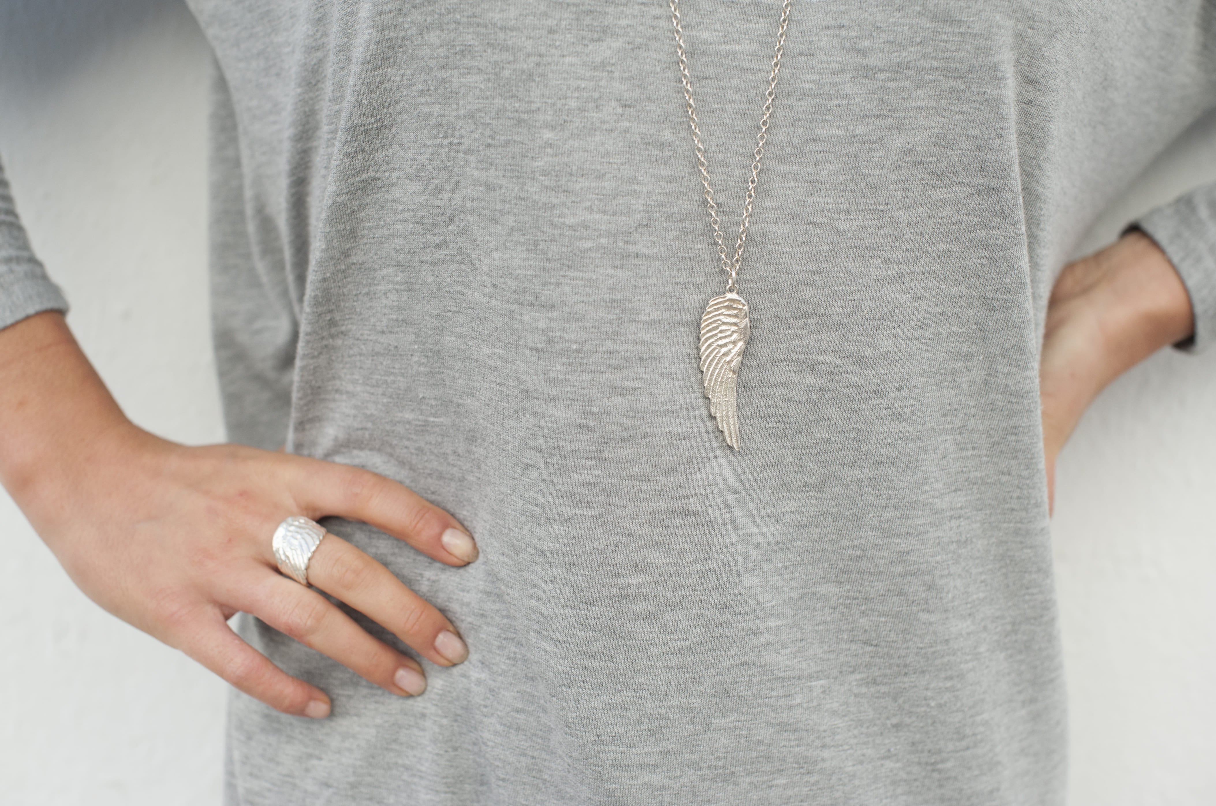 Model dressed in grey wearing the angel wing necklace and ring made in silver handcrafted by Jennifer Kinnear.