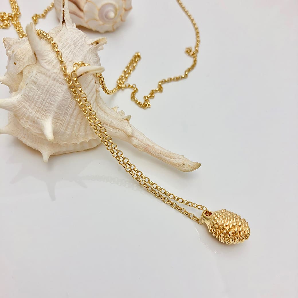 Goldplated pinecone necklace displayed on a seashell handcrafted by Jennifer Kinnear.