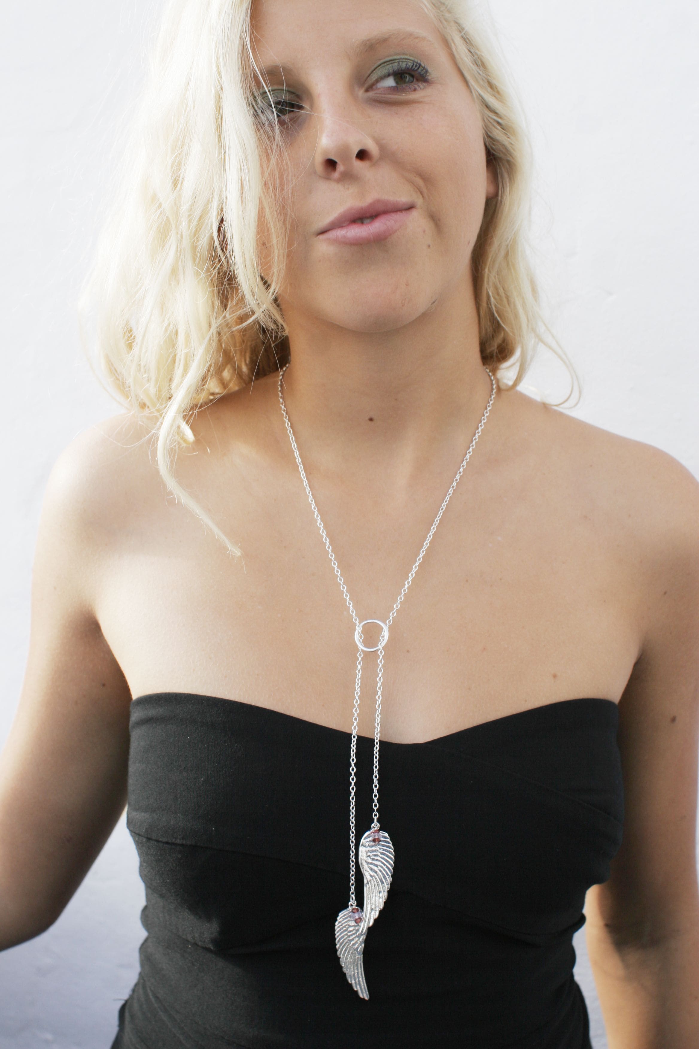 Blonde model in a dark dress wearing the double angel wing made in silver handcrafted by Jennifer Kinnear.